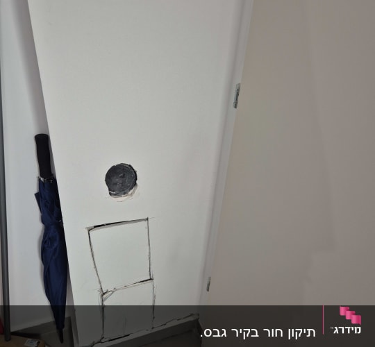 קיר עם חור ותיקון גבס ליד מטאטא ומטריה
